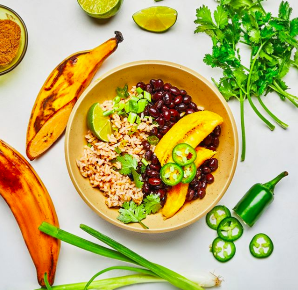 A bowl containing rice, fruit, veggies, and more