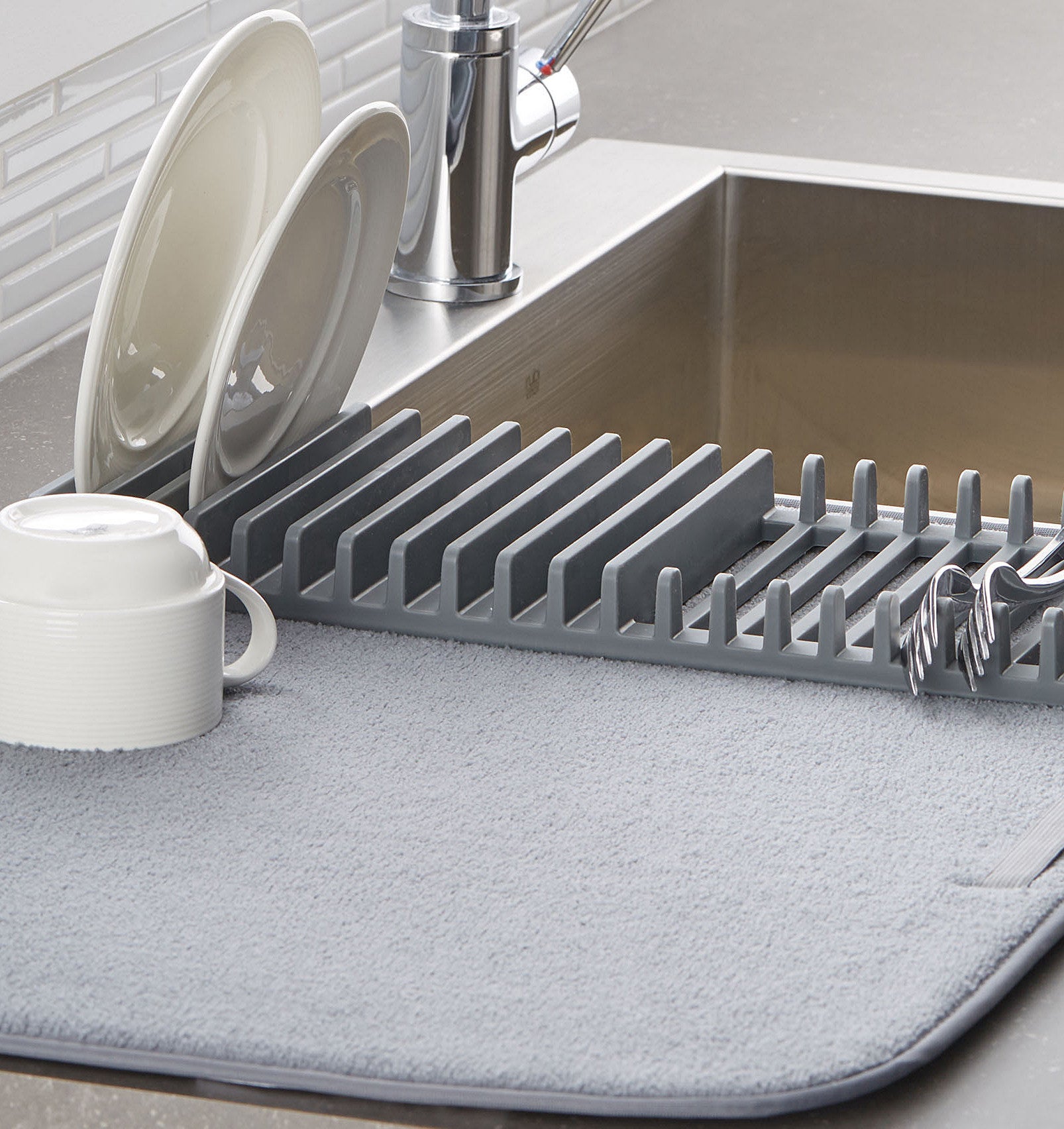 A microfibre mat with silicone dividers on one side with dishes and flatware drying