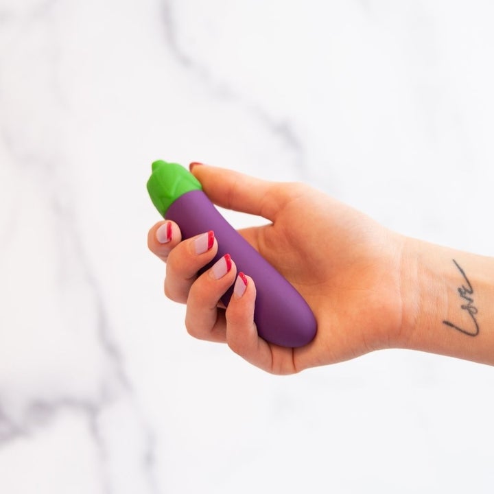 a hand holding the purple and green toy 
