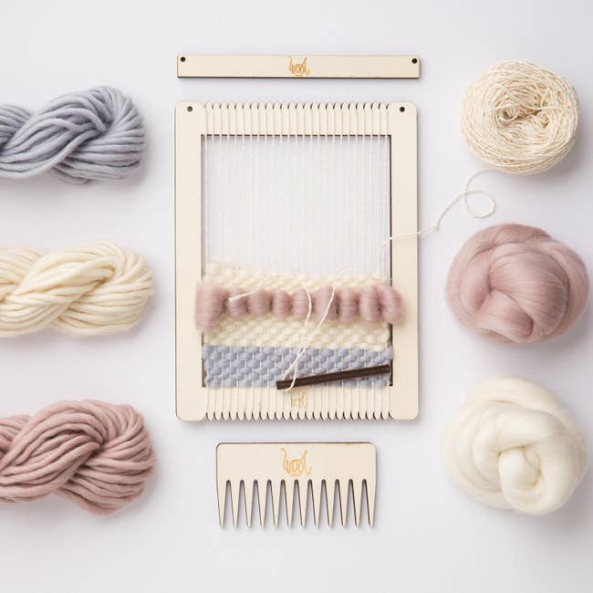 A weaving look with half of a project completed on it in dusty pink, blue, and ivory 