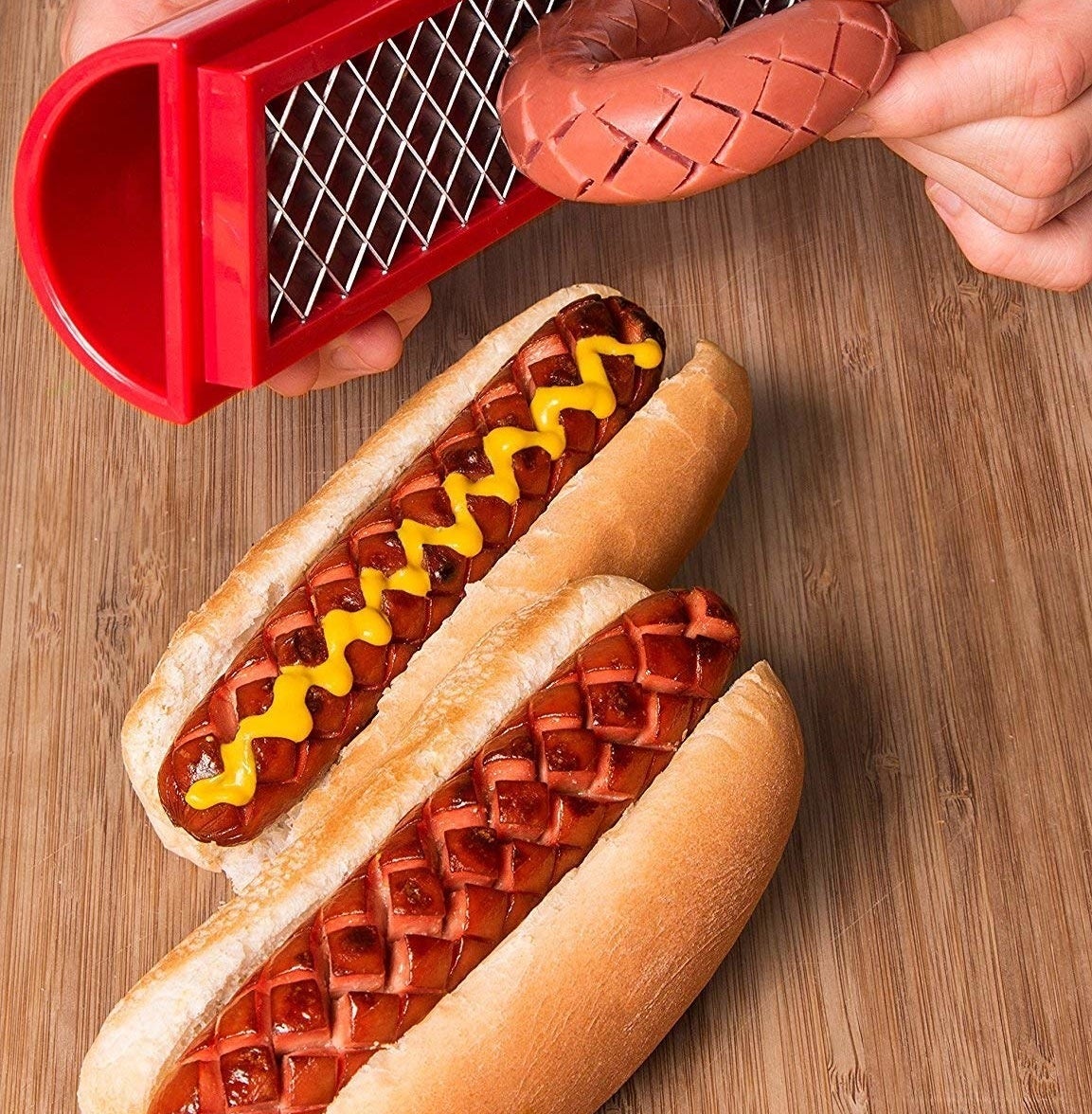 A person using the slicer on a hot dog