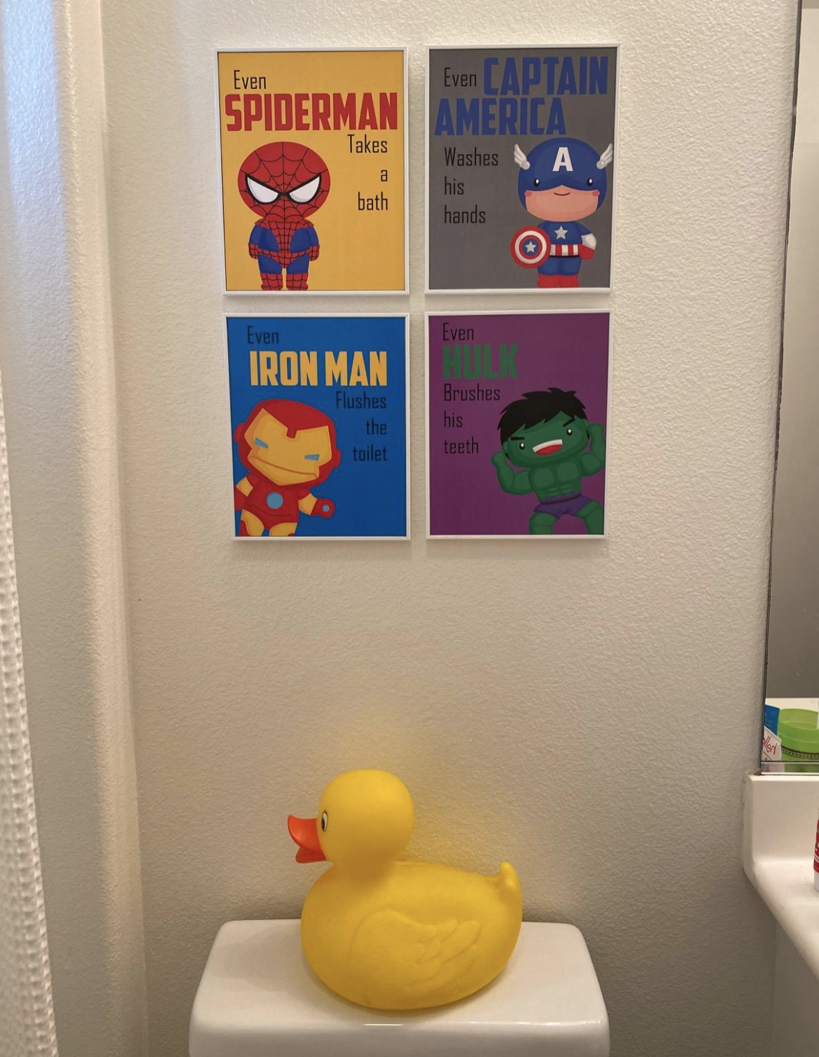 Four photos with child-like cartoons of superheroes. Reading clockwise, the signs say &quot;Even Spiderman takes a bath,&quot; &quot;Even Captain America washes his hands,&quot; &quot;Even Iron Man Flushes the toilet,&quot; and &quot;Even Bulk brushes his teeth.&quot;