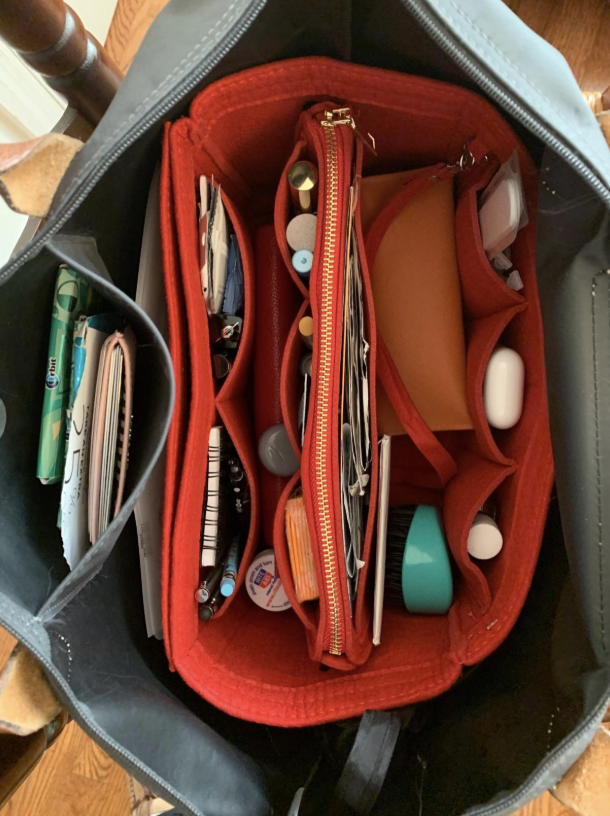 the insert being used inside a purse with all of the reviewer&#x27;s things organized neatly 