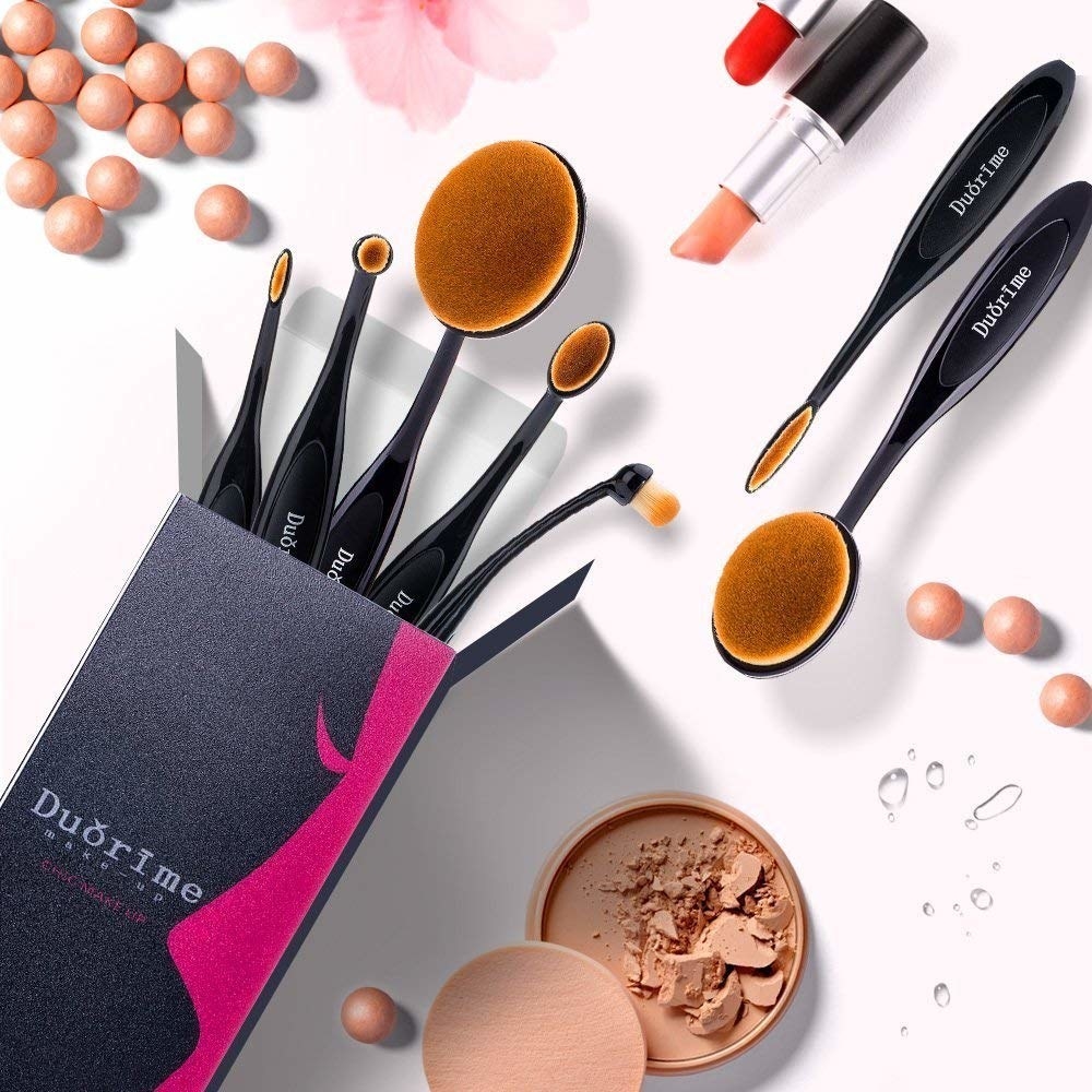 A set of makeup brushes popping out of a small rectangular box Each brush has a oval-shaped head