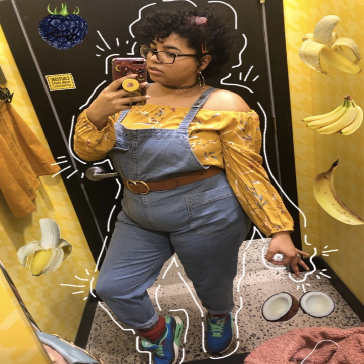 Reviewer wears same style overalls with a yellow off-shoulder blouse and colorful sneakers