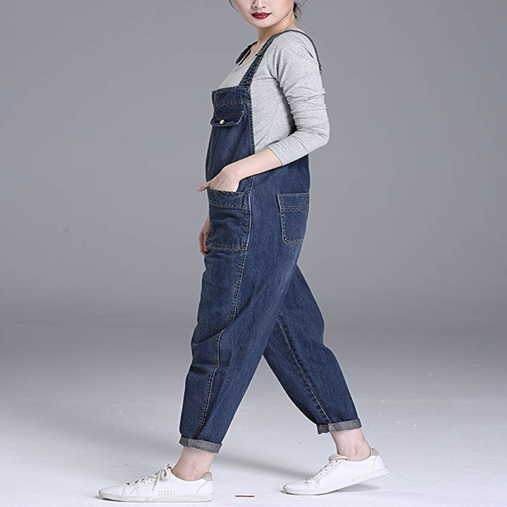 Model wears blue baggy overalls with a gray shirt and white sneakers