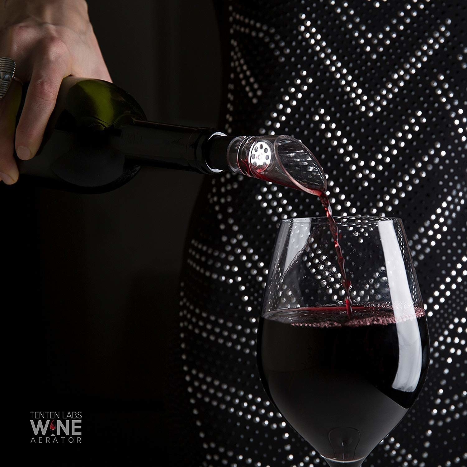 A person pouring red wine through the aerator into a glass