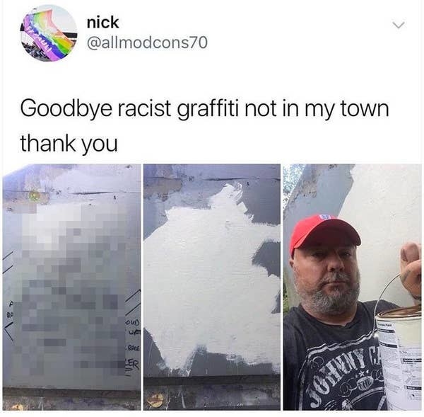 man painting over racist garffiti