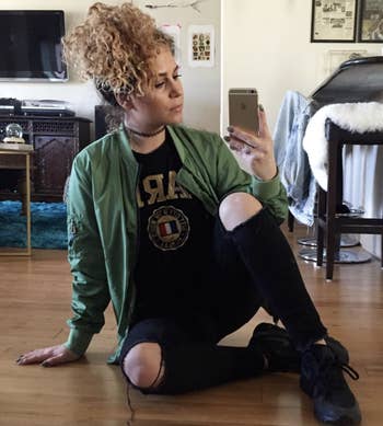 Reviewer wears dark green bomber jacket with distressed black jeans
