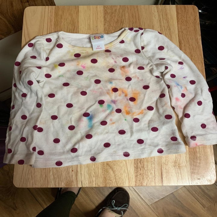 Child's shirt with orange, yellow, and blue stains on it
