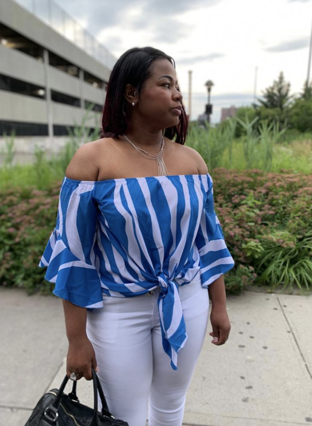 Reviewer wears blue and white striped off-shoulder top with white pants
