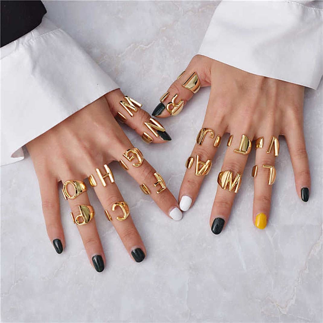 A model with the chunky gold rings in a variety of letters across many fingers