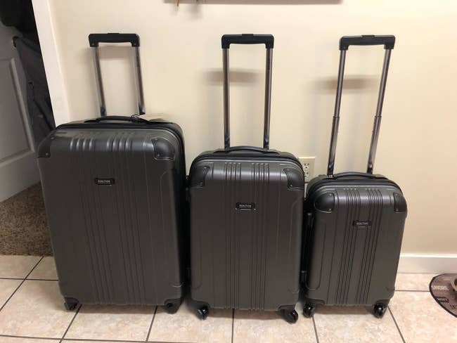 reviewer photo of three black rolling suitcases lined up against a wall in descending size order