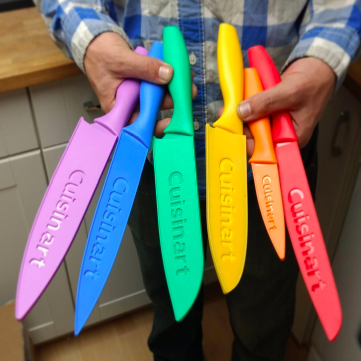 a reviewer holding the knife set with the covers on the knives in their hands