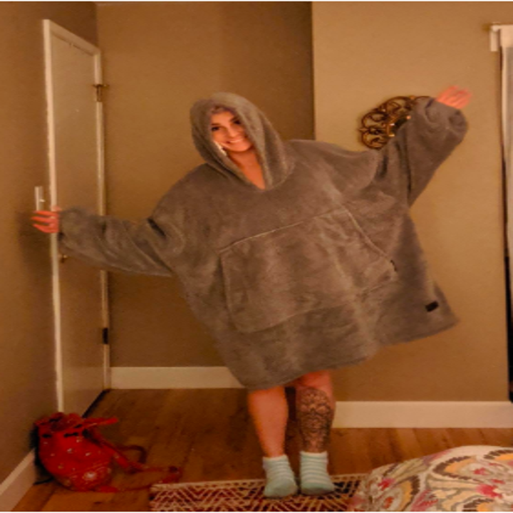 A reviewer wearing the giant oversize fleece hoodie with huge pocket in gray
