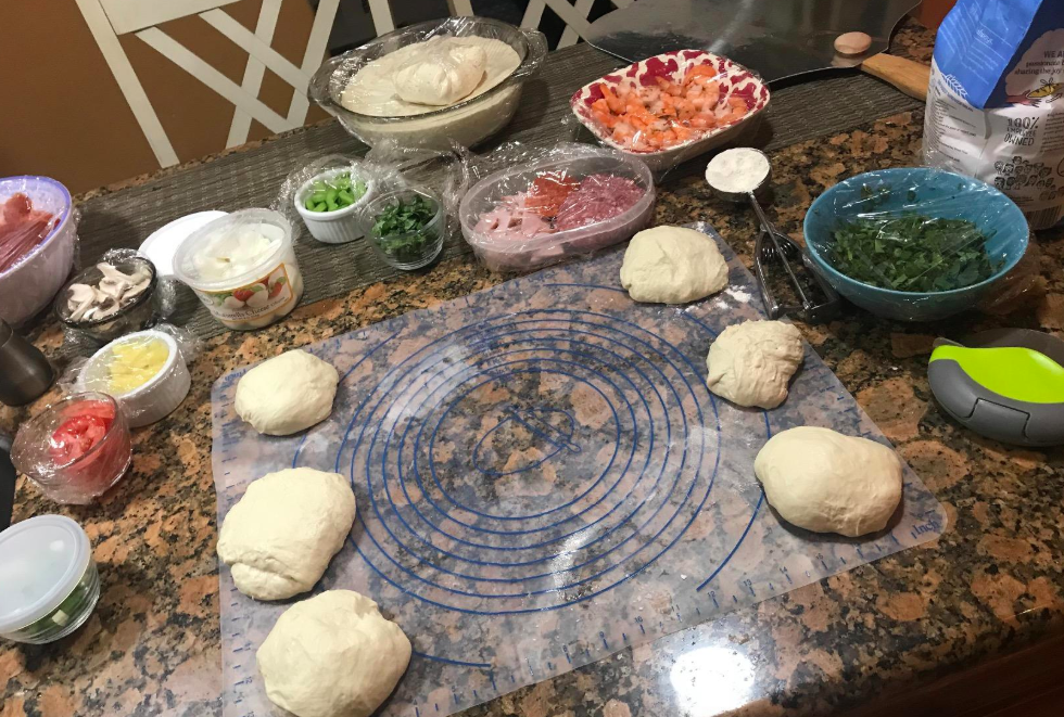 the mat with pizza dough on it and pizza toppings laid out on a counter