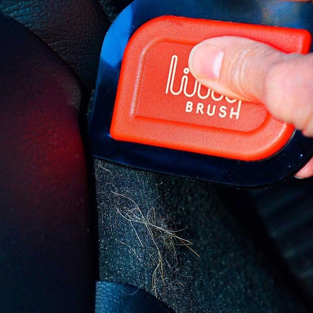 A person using the pet hair detailer to remove pet hair from a car seat