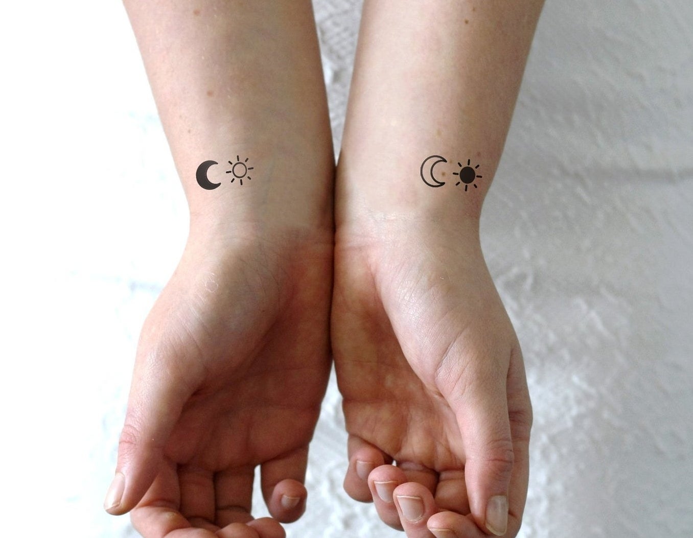 A set of tattoos with a moon and sun on two wrists 
