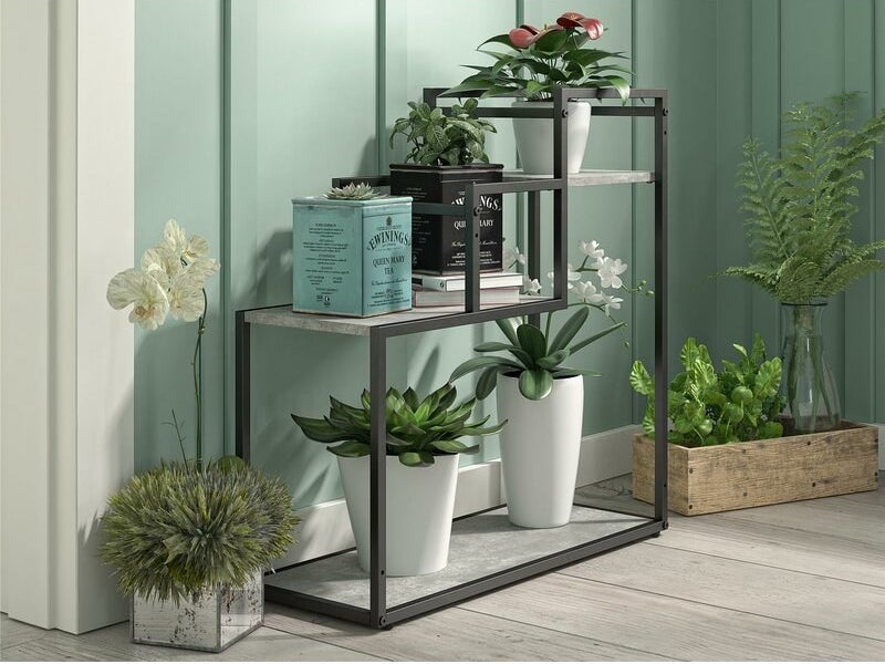 A three-level plant stand with a dark metal frame and marble-colored shelving