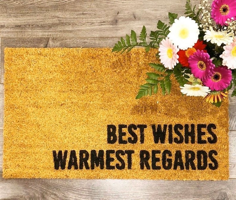 The brown doormat with &quot;Best wishes warmest regards&quot; written on it in black letters