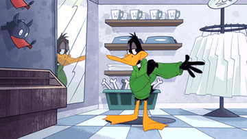 Daffy Duck trying on a hoodie and checking himself out in a mirror 