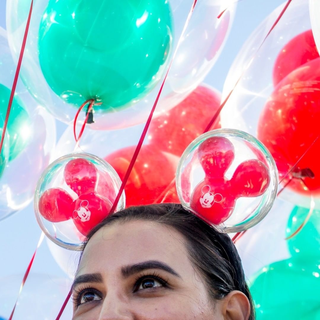 a model wearing the balloon ears - they have two plastic balls with red mickey balloons inside