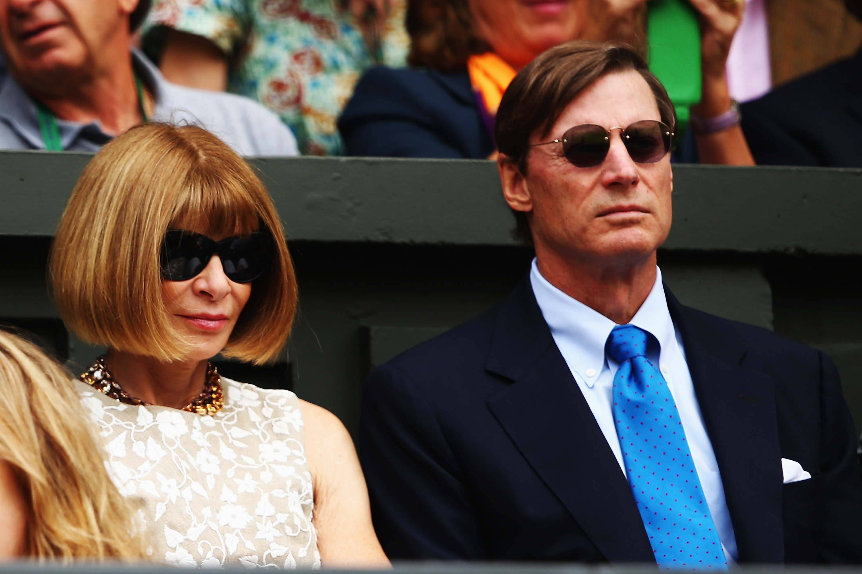 at a tennis match in glasses looking intimidating