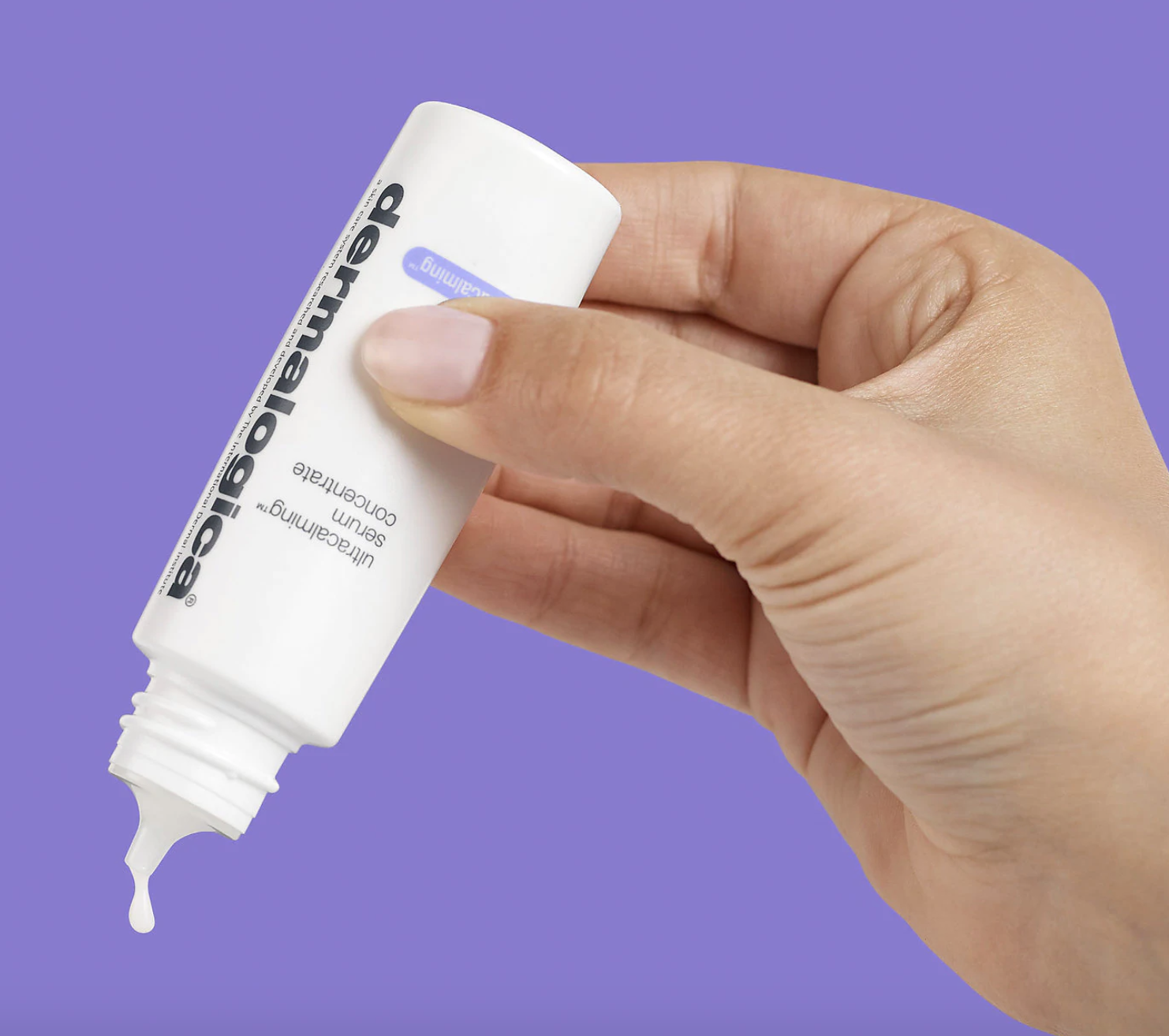 hand squeezing white bottle with nozzle labeled &quot;dermalogica&quot; 