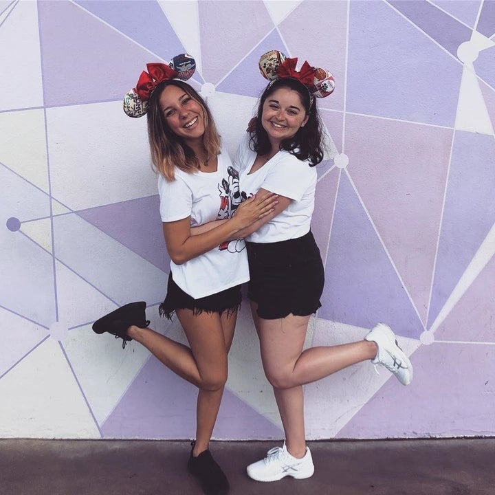 two people standing in front of the purple wall at disney in matching minnie ears