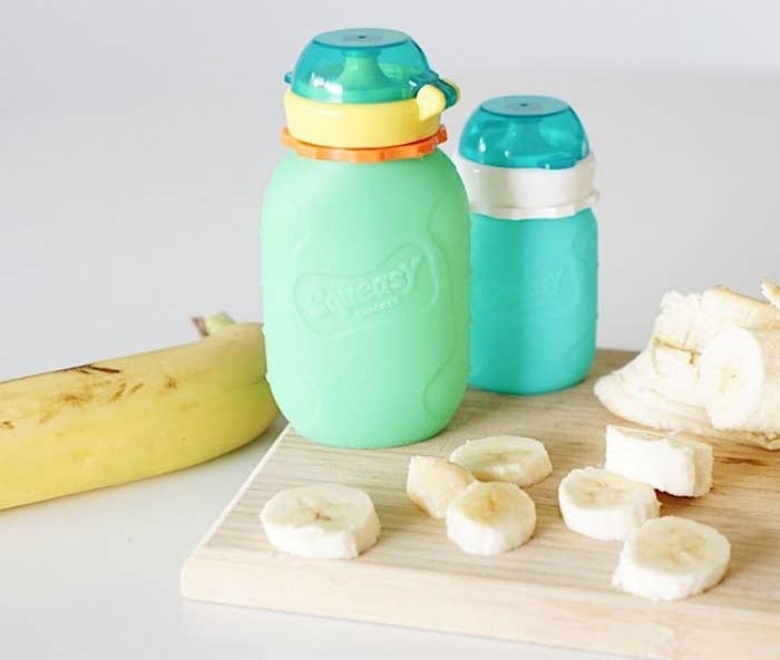 A small bottle with a lid placed on a wooden cutting board with chopped bananas on it