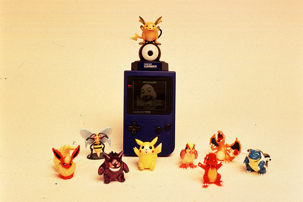 A Game Boy Camera with Pokémon figurines around it