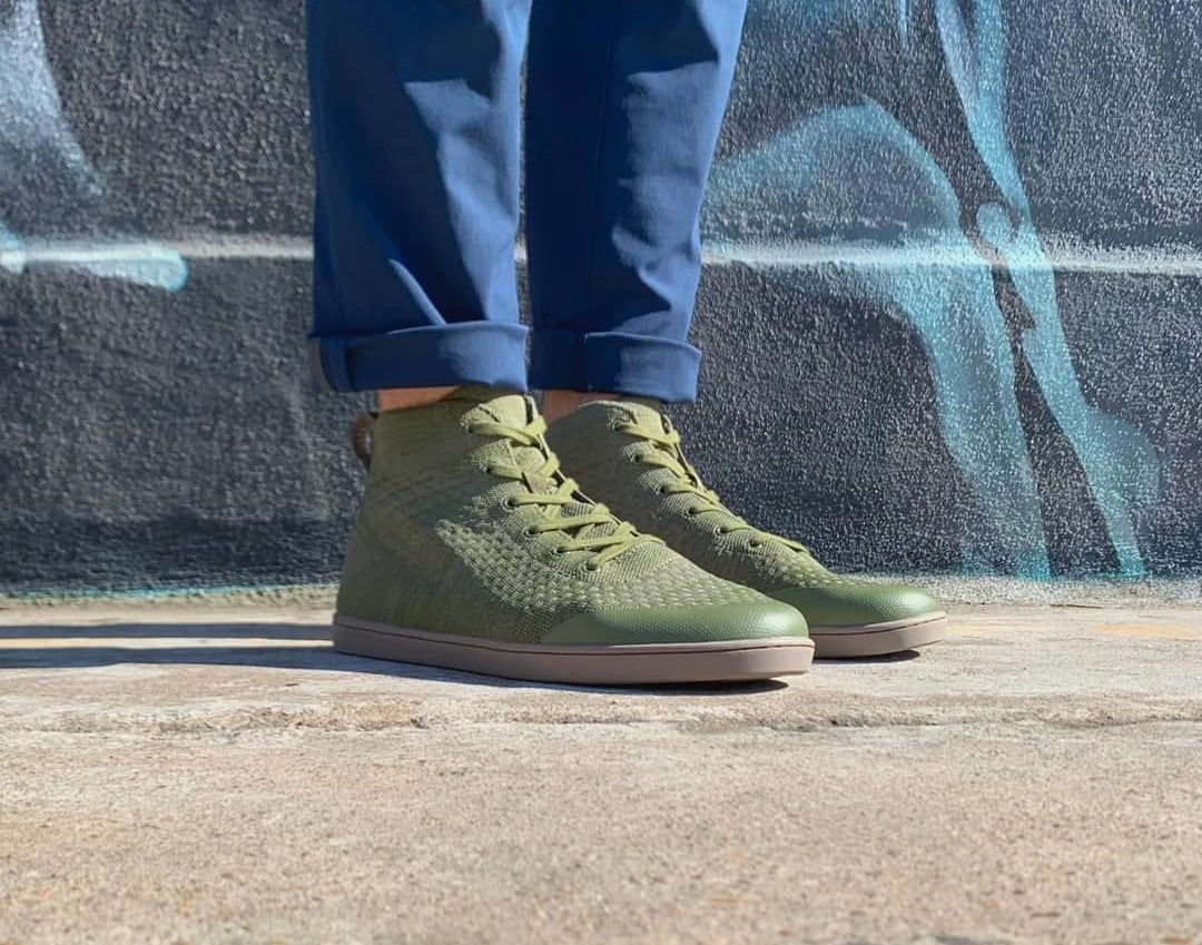 Model wearing the knit high-top shoes in olive with brown soles