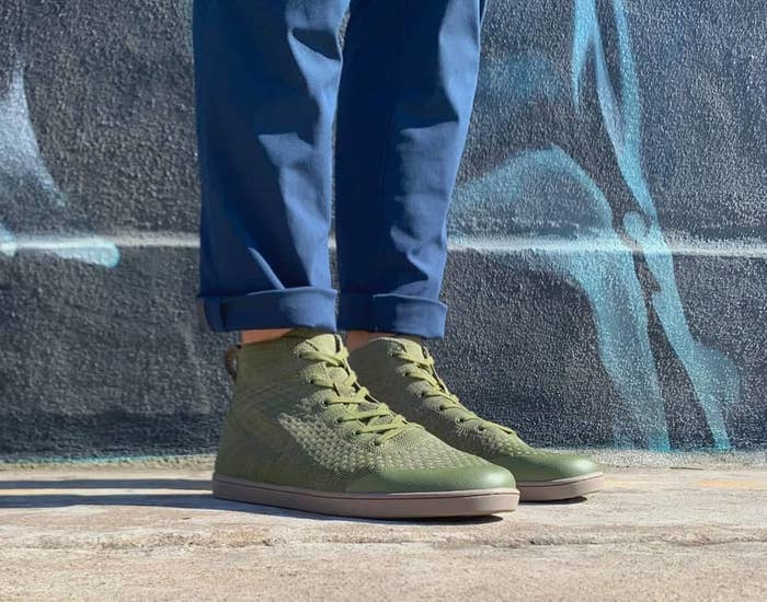 Model wearing the knit high-top shoes in olive with brown soles