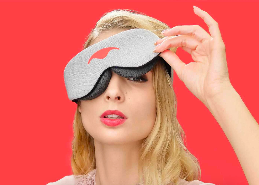 A model wearing the sleep mask and lifting one eye 