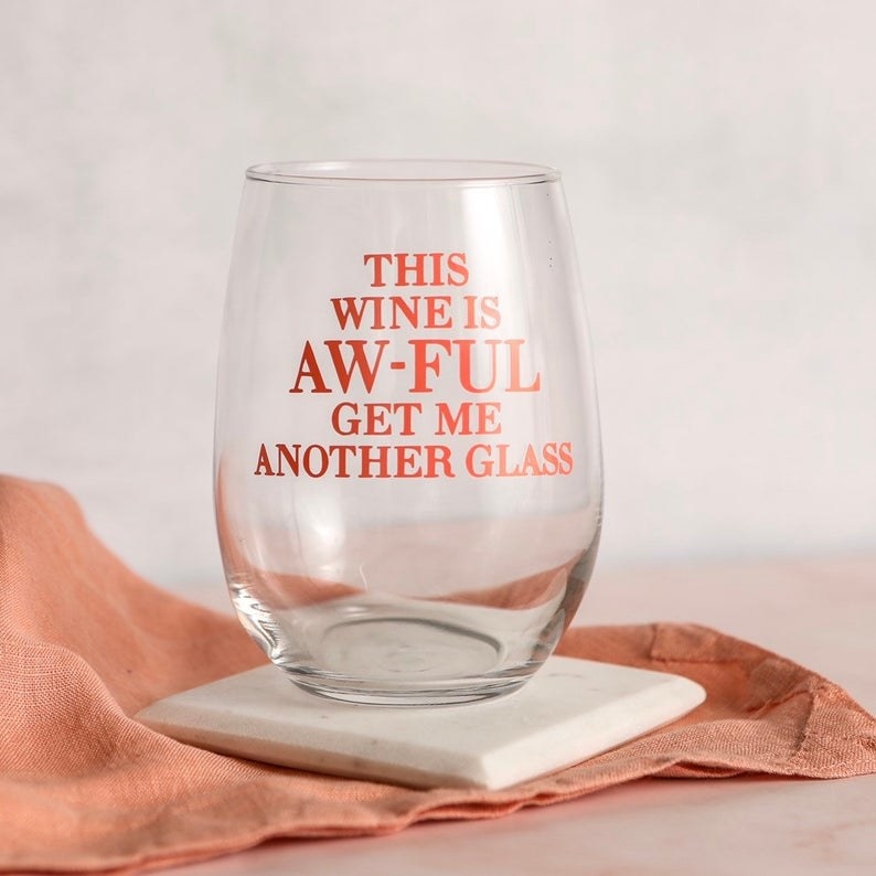 The stemless glass that reads &quot;This wine is aw-ful get me another glass&quot;