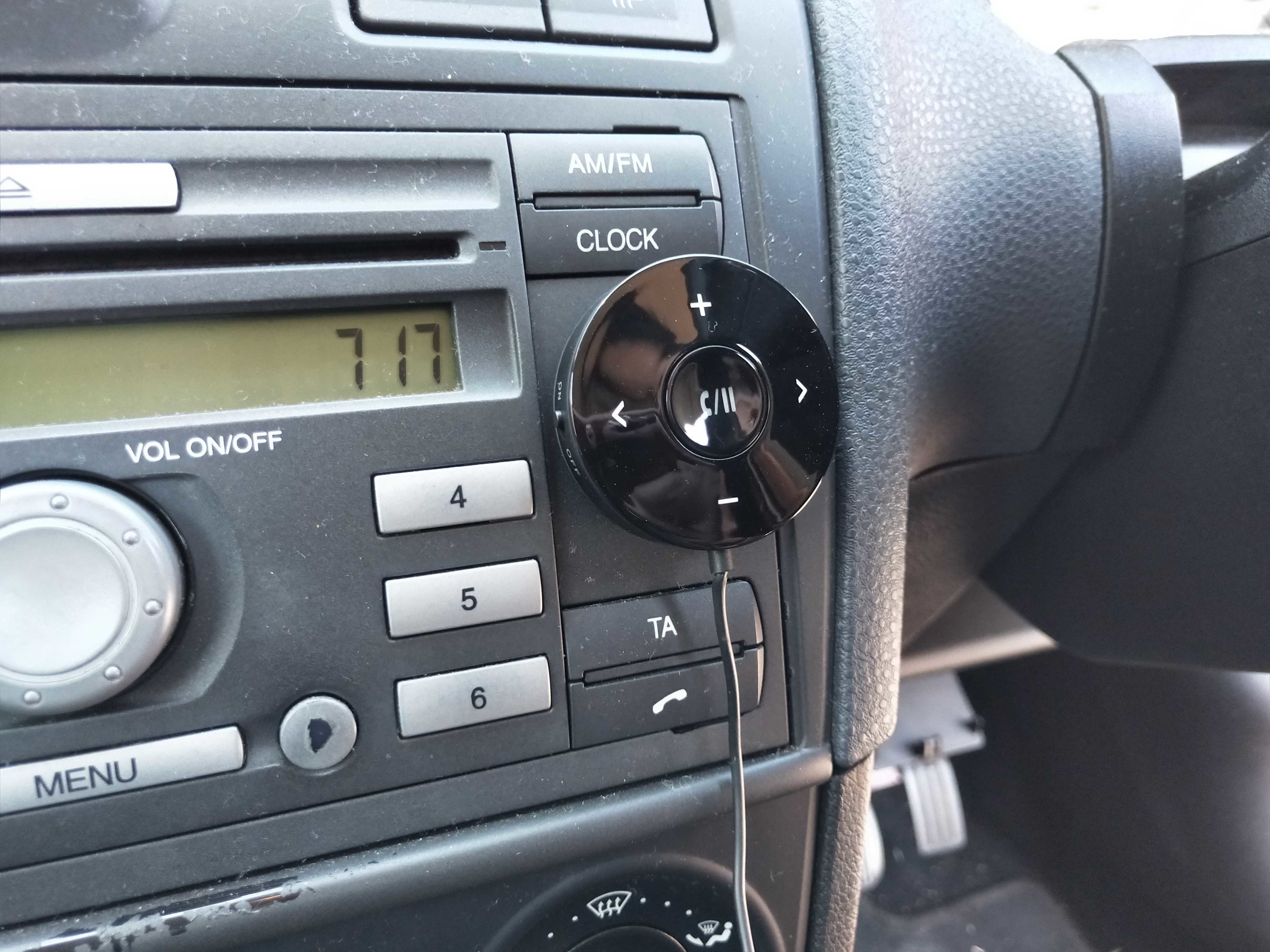 Round Bluetooth receiver attached to car centre console.