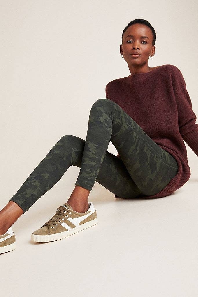 Model sitting on the floor while wearing the Spanx seamless leggings in camo.