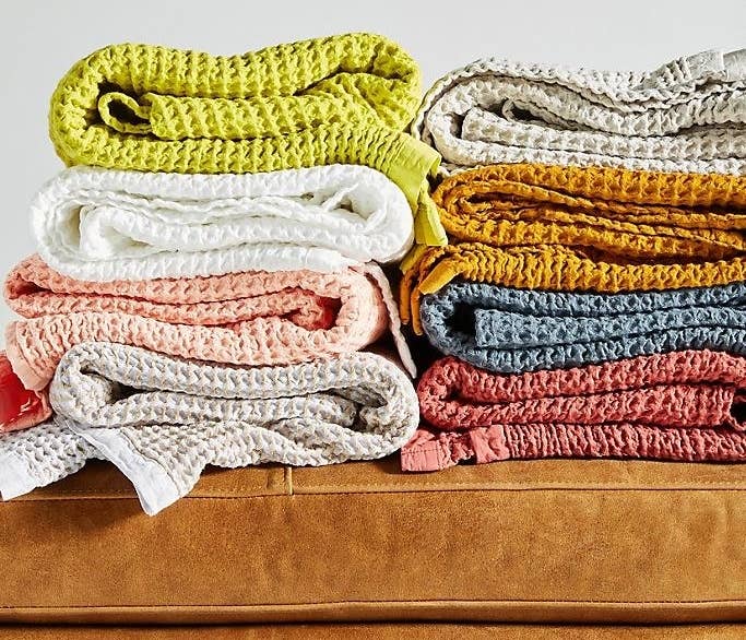 Folded piles of the waffle throw blankets in multiple colors. 