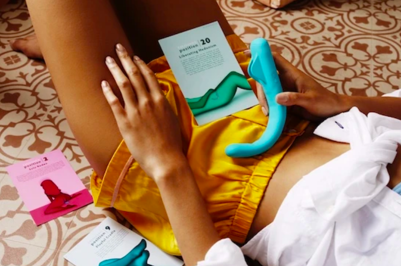 A person holding the smooth &quot;j&quot; shaped vibe with the instruction cards out