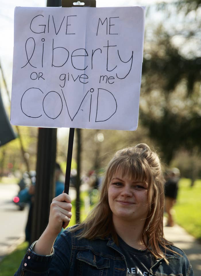 Woman holding a sign reading, &quot;Give me liberty or give me COVID&quot;