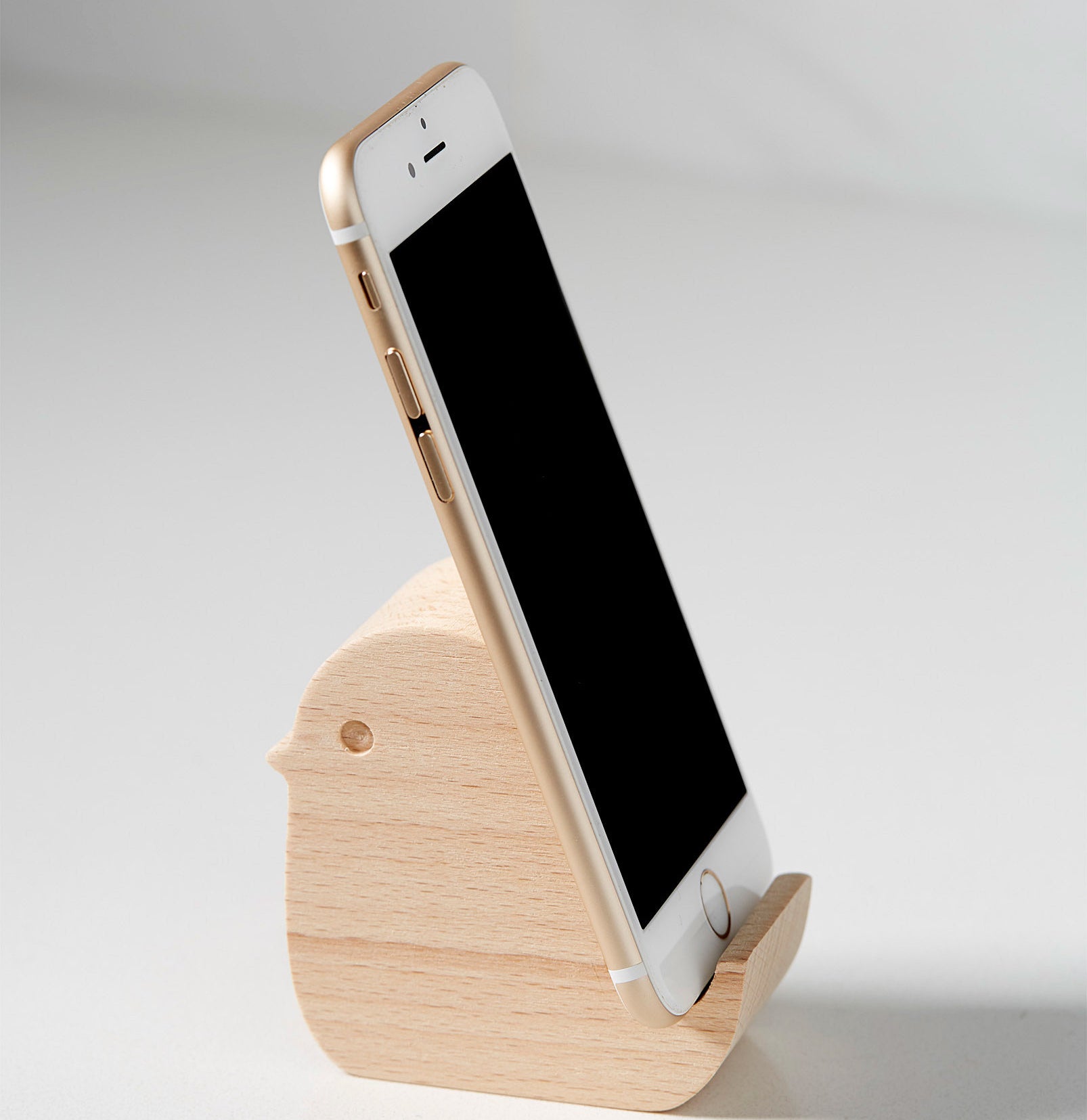 A wooden phone holder in the shape of a small bird