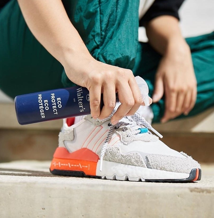 A person spraying their shoes with the solution