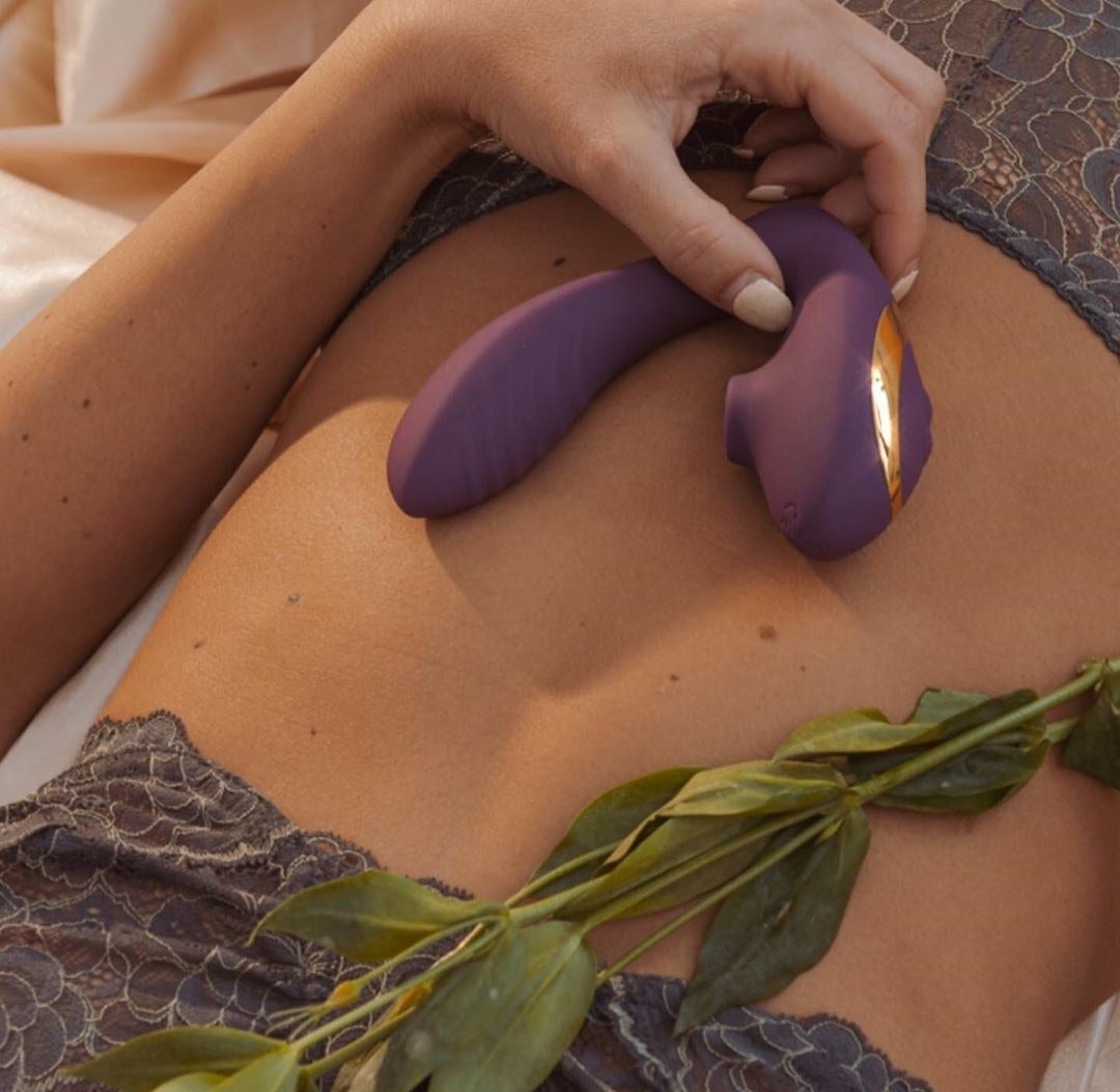 Model holding the curved vibrator to show its two-in-one G-spot and clitoral design 