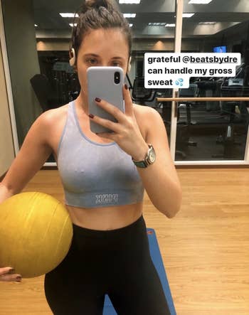 BuzzFeed editor Emma McAnaw wears white Powerbeats Pro Wireless Earphones while working out at the gym