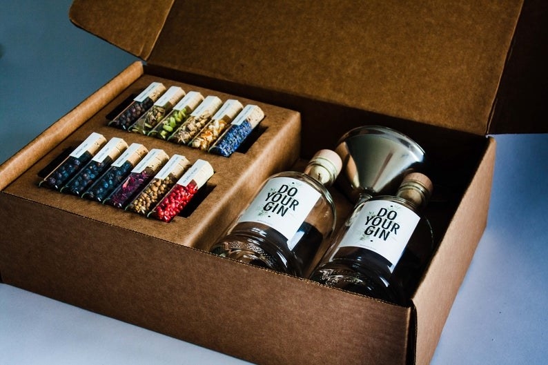 A box filled with two labeled bottles, a stainless steel funnel, and 12 vials of herbs 