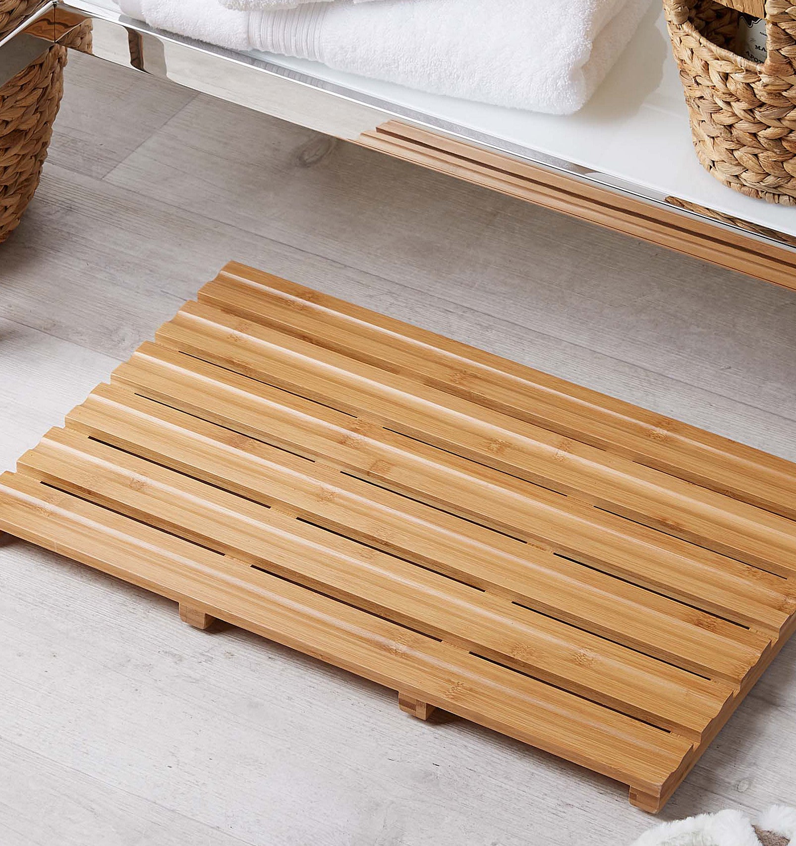 A slatted wooden bath mat in front of a bathroom sink