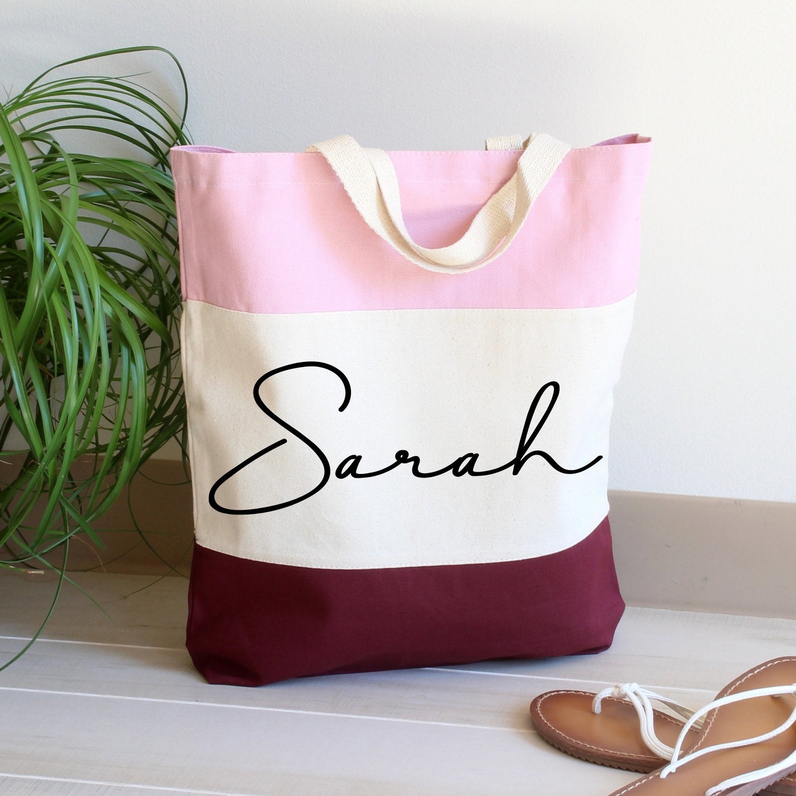 the pink, white, and red tote bag with the name &quot;sarah&quot; printed on it in black ink