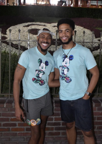 two reviewers wearing light blue tees with a tropical mickey on it