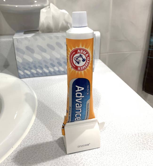 reviewer photo of the white holder with toothpaste inside 