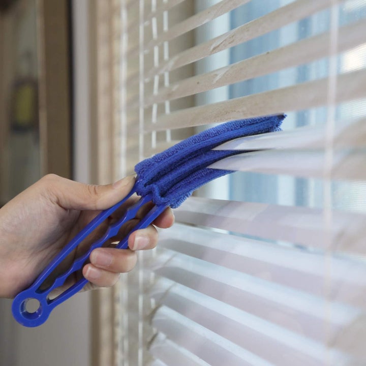 blue three-cloth duster brush going through window blinds
